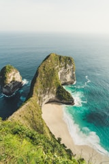 rock formation beside ocean under white clouds during daytime