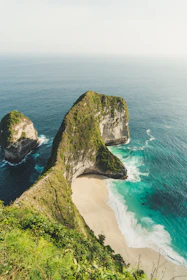 rock formation beside ocean under white clouds during daytime