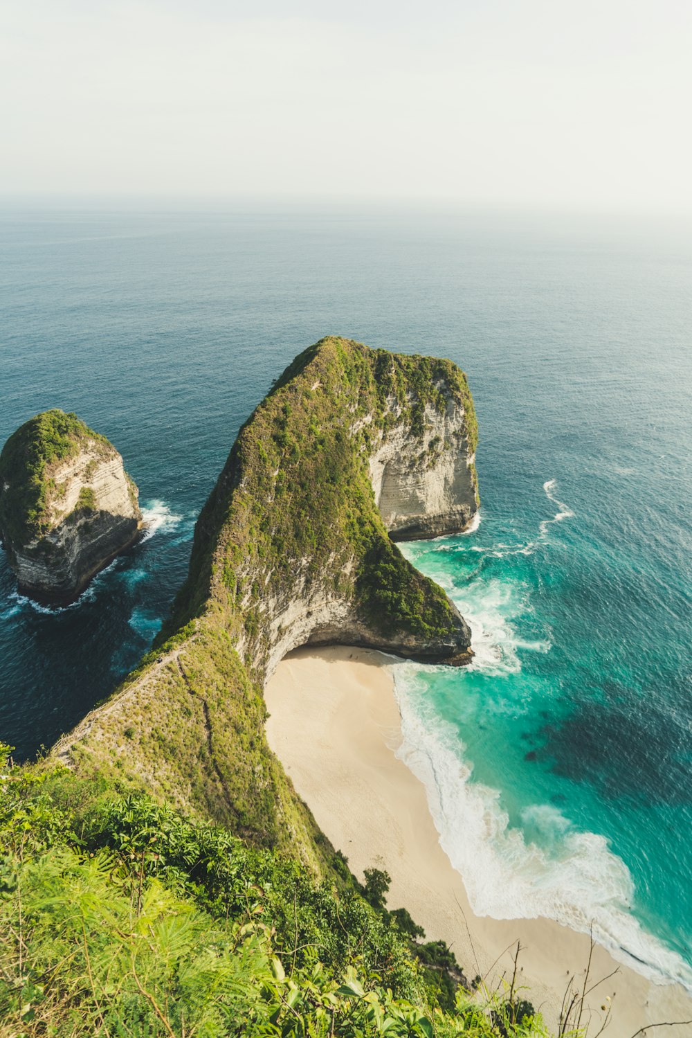 rock formation beside ocean under white clouds during daytime