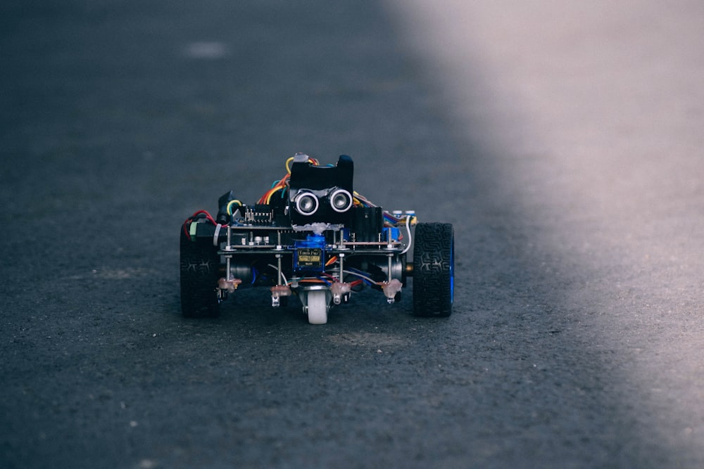 black and blue RC car on gray pavement