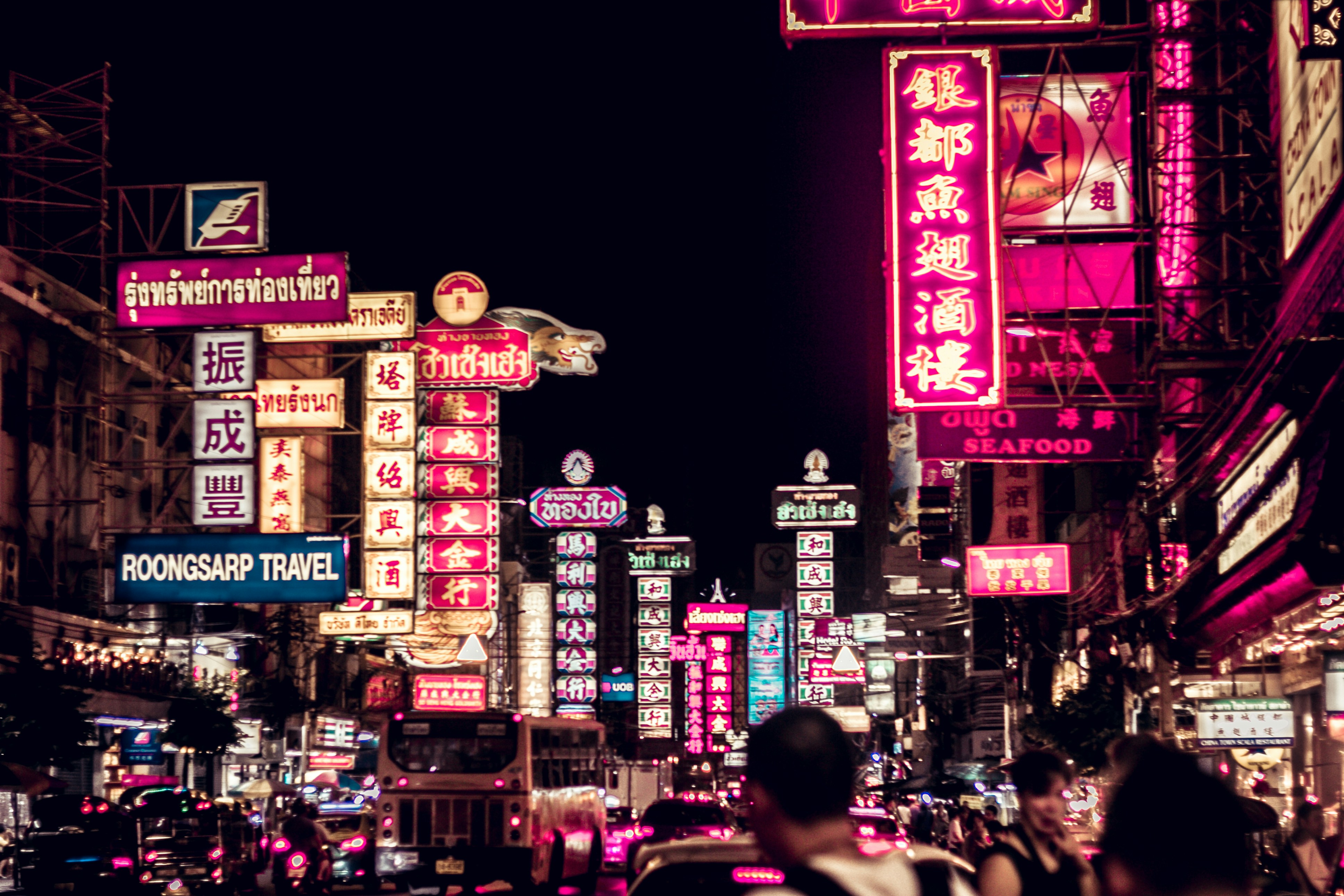 people walking along road filled with LED signages, Chinatown in Thailand