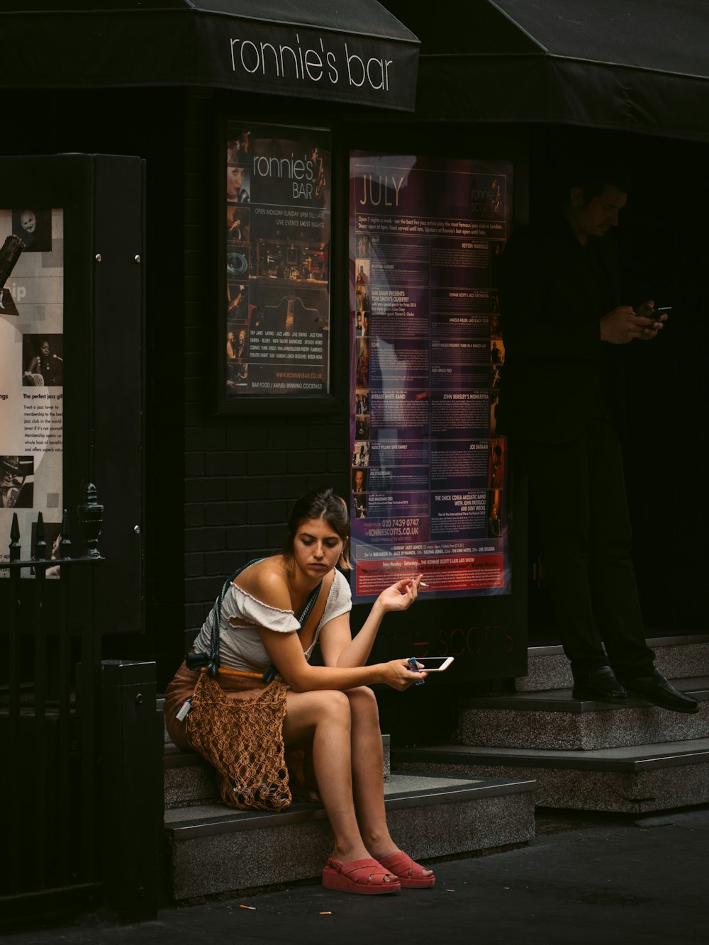 woman holding smartphone sitting on Ronnie's Bar store