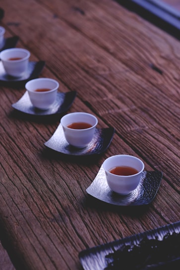 inline white ceramic bowls filled with brown liquids on brown wooden table