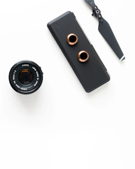 A sleek drone accessory kit laid out on a baby blue background with black and orange accents.