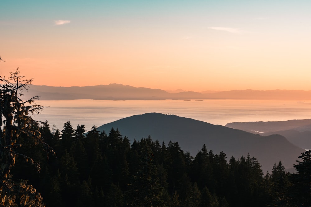 photo of mountain, body of water, and forest during sunset