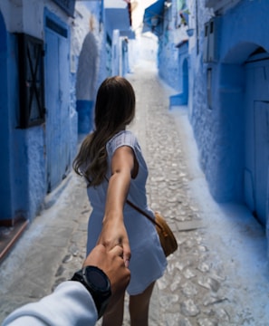woman holding man's hand while walking on alley