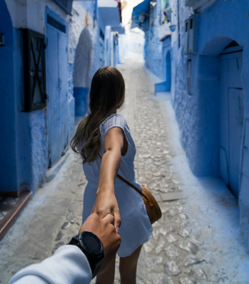woman holding man's hand while walking on alley