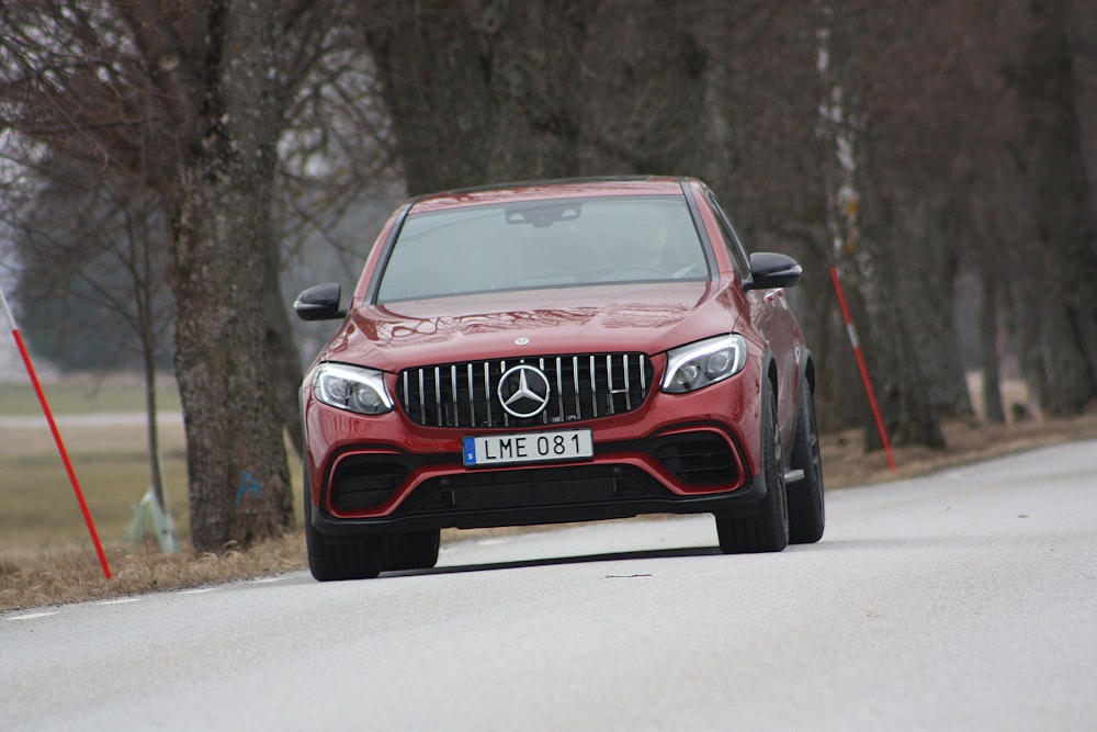 Vehículo Mercedes-Benz rojo en la calzada cerca de árboles