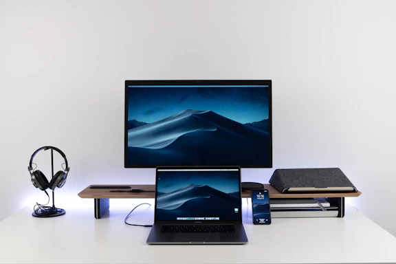 A sleek, minimal desk setup with a laptop, notebook, and a soft neutral-toned background.