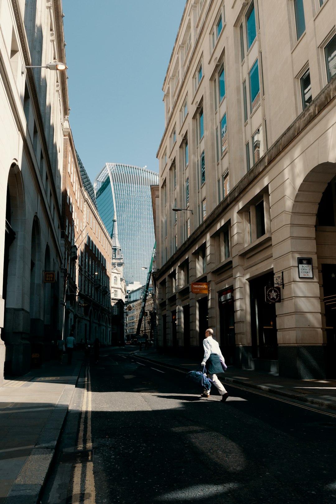 person walking on gray road between buildings