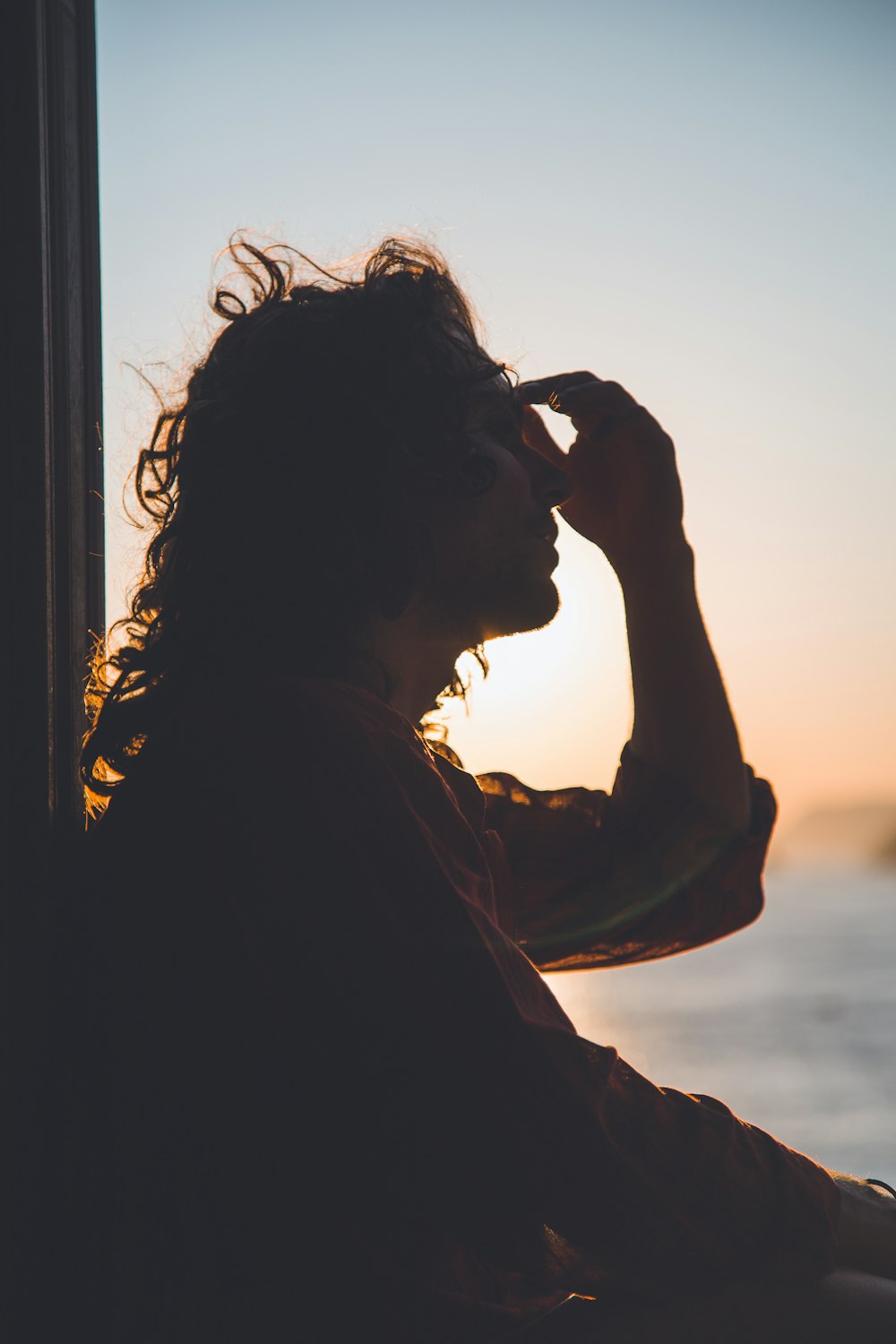 man holding forehead under sunset