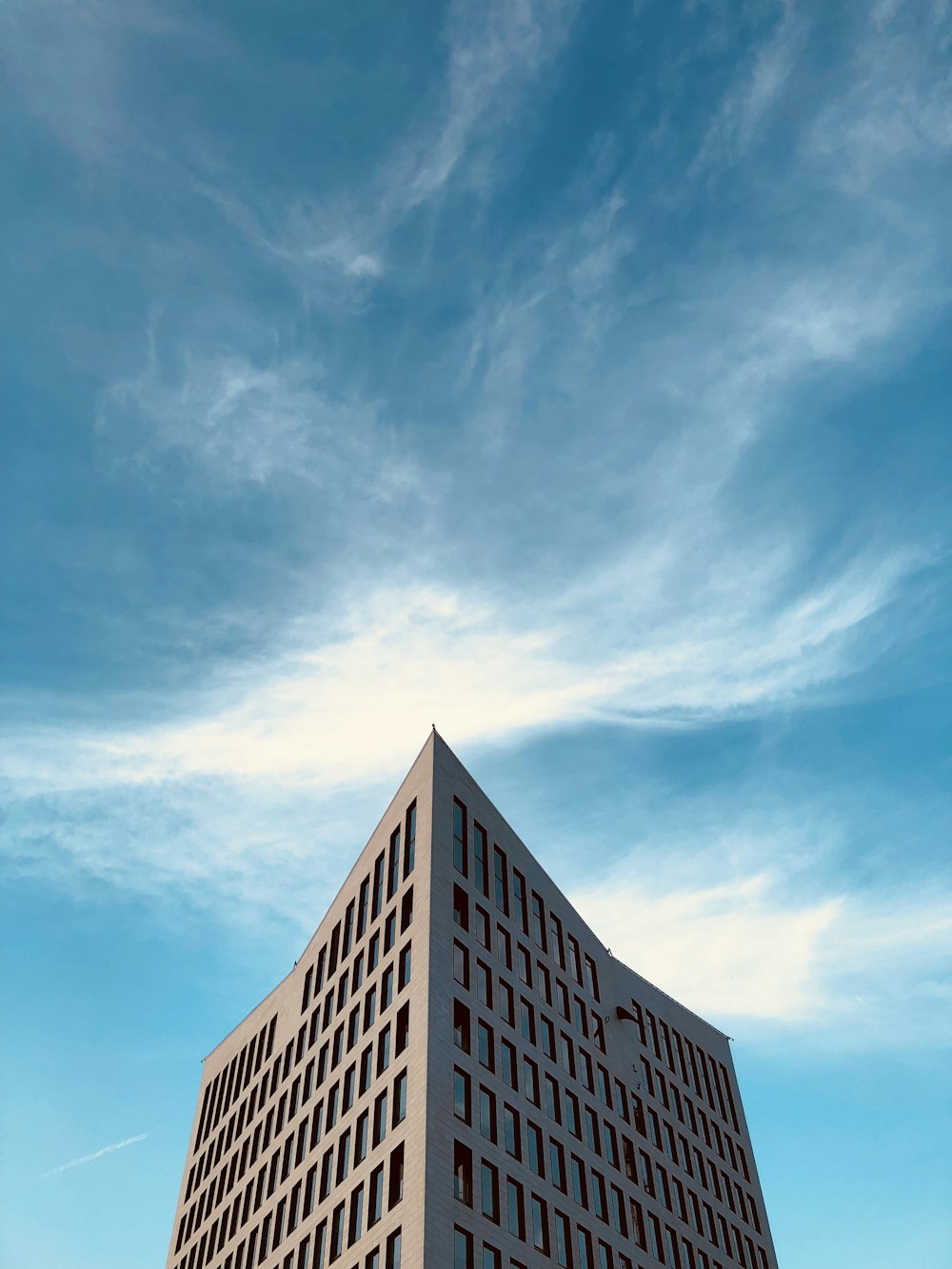 low-angle photography of high rise building under white clouds at daytime