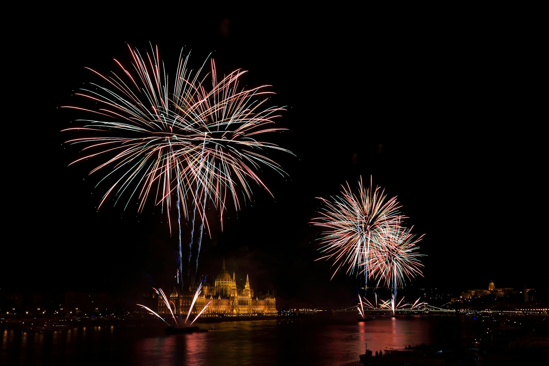 fireworks over temple near calm body of water