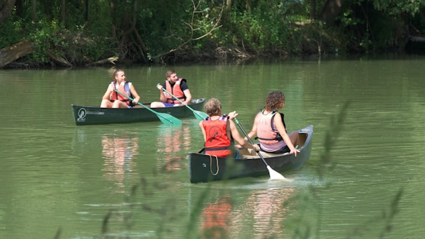 Friends laughing and splashing water while canoeing together.