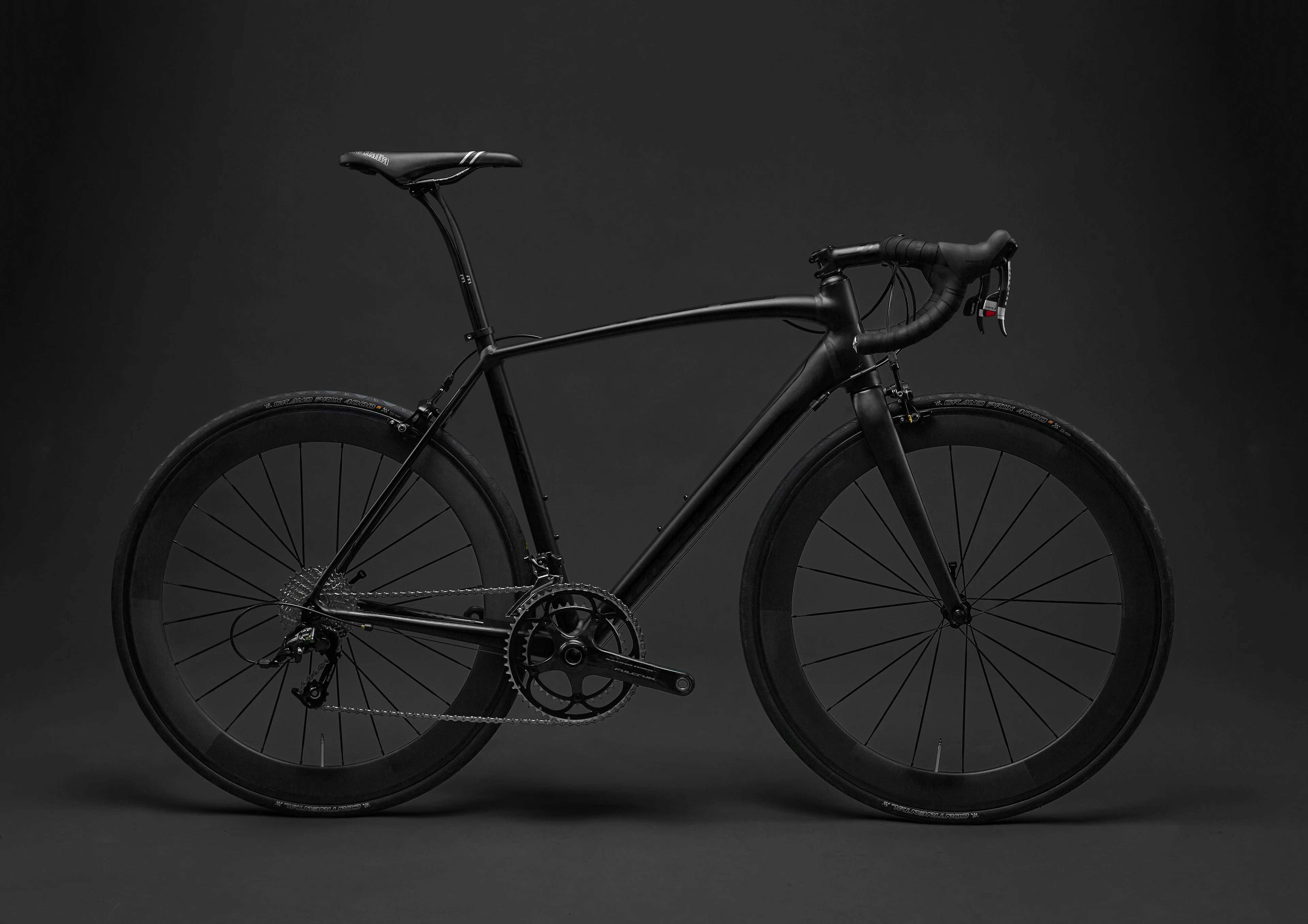 A matte black road bicycle in a studio