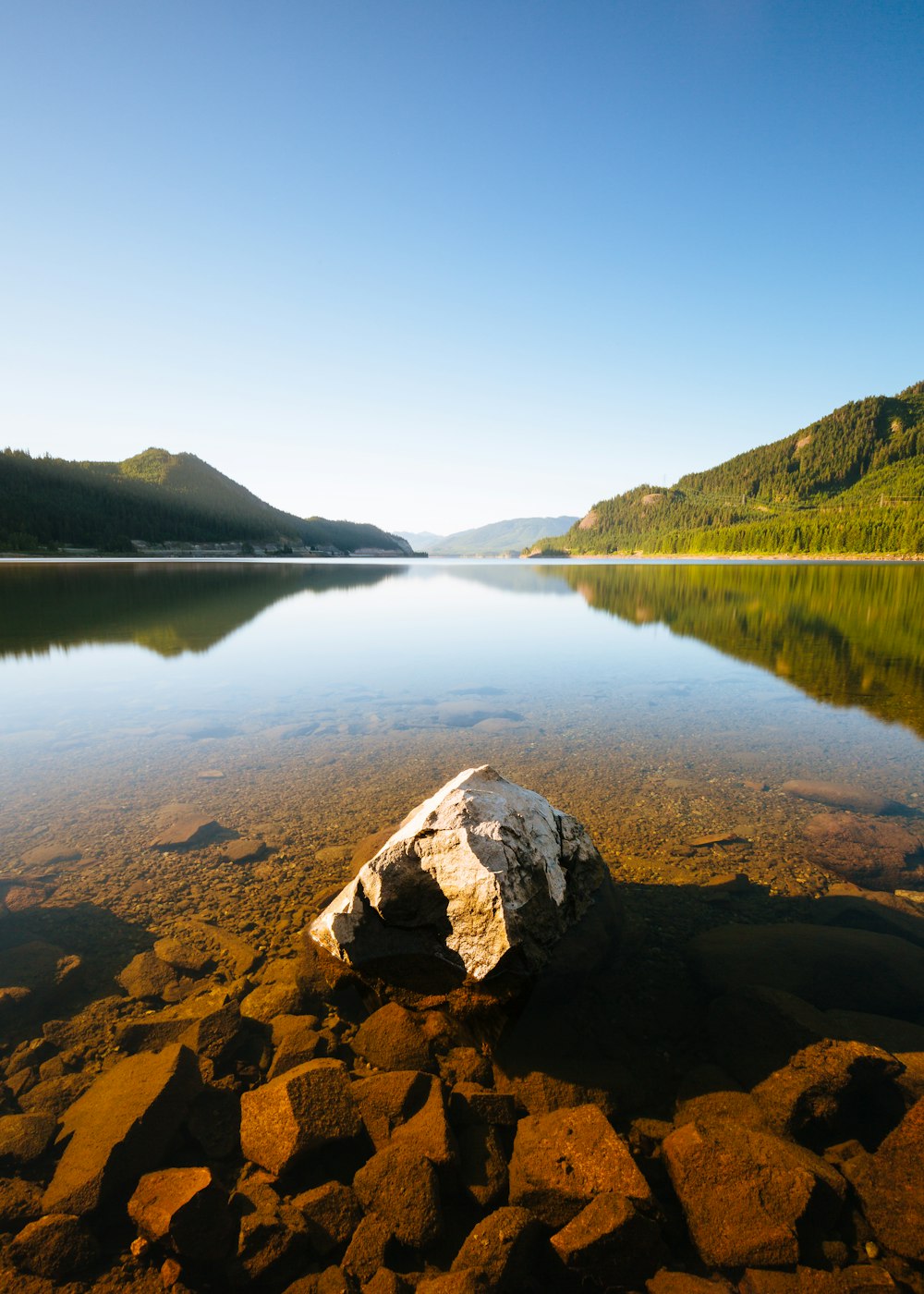 photo of calm body of water between mountain