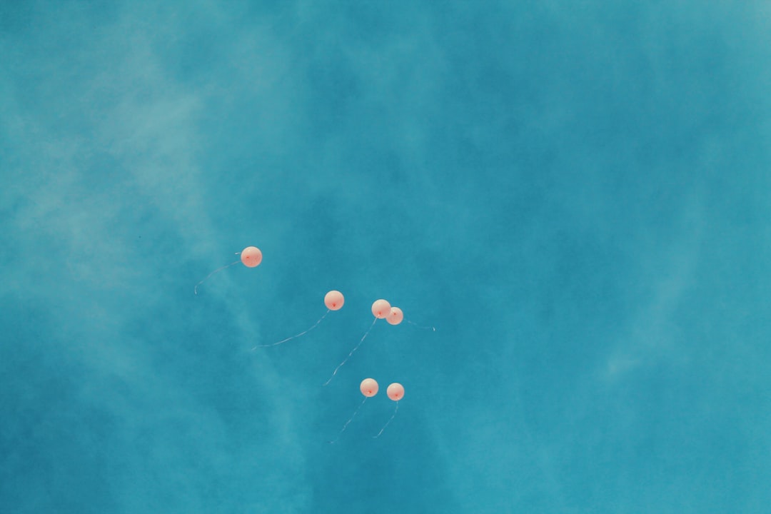 low angle view of six orange balloons during blue sky