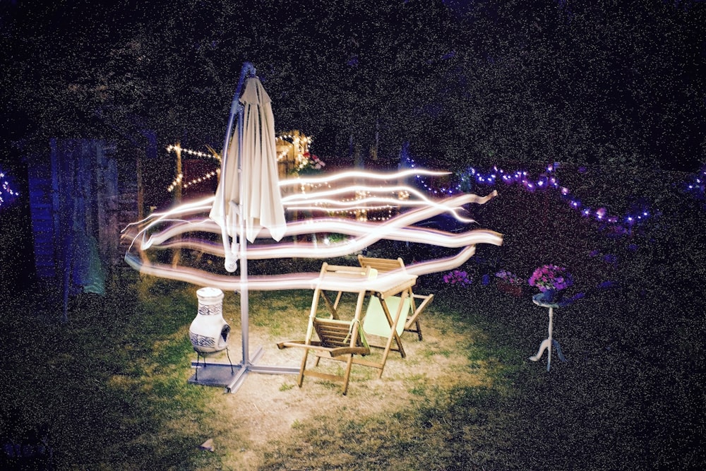 Fotografía de lapso de tiempo de luces sobre sombrilla en voladizo y sillas plegables durante la noche