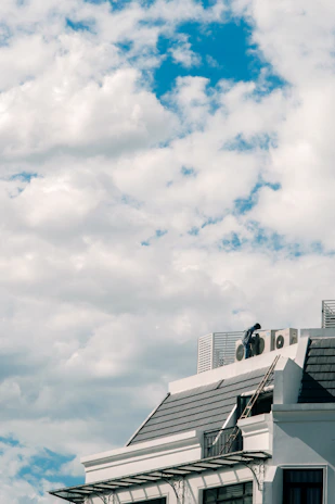 Close-up of a technician repairing a large HVAC system on a rooftop under a clear sky.