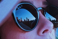 Close-up of a stylish pair of sunglasses reflecting cityscape views.