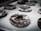 Several chocolate donuts with a dusting of powdered sugar are resting on a baking sheet lined with parchment paper. The donuts are arranged in rows and appear to be freshly baked.