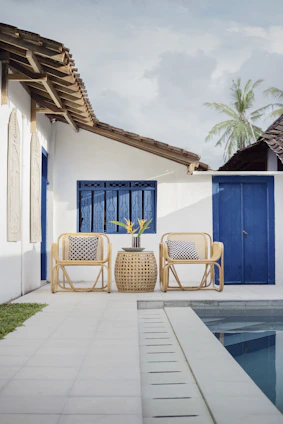 A sunlit patio featuring a coastal patio set with breathable mesh chairs and a backless bench beside a shimmering pool.