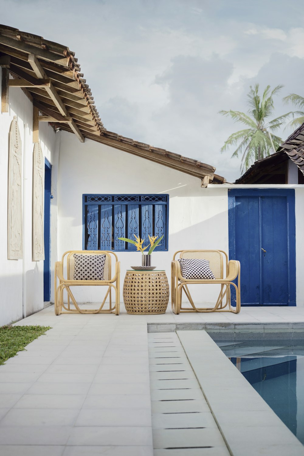 mesa de vime e duas cadeiras perto da piscina