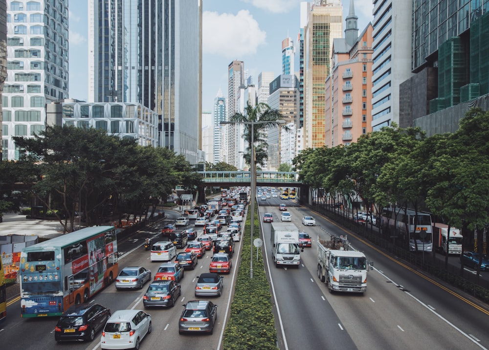 vehicles traveling on road between buildings during daytime