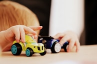 Close-up of a child’s hand holding a bright plastic toy car from kotomoto’s collection.