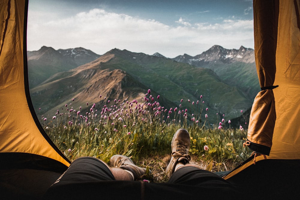 person lying inside tent and overlooking mountain