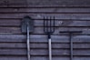 brown shovel and two rakes on brown wooden surface