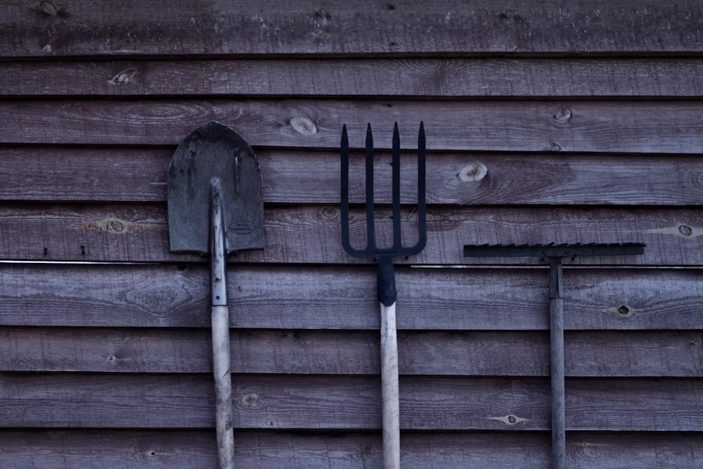 brown shovel and two rakes on brown wooden surface
