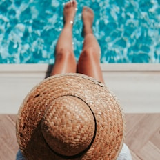 woman sitting on poolside setting both of her feet on pool