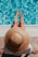 woman sitting on poolside setting both of her feet on pool