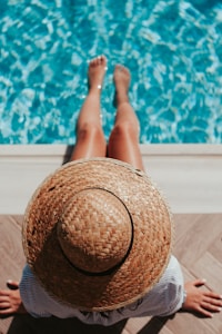 woman sitting on poolside setting both of her feet on pool