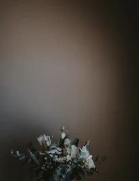 Elegant wedding floral wreath with white roses and greenery on a minimalist white background.