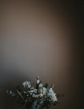 Elegant wedding floral wreath with white roses and greenery on a minimalist white background.