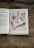 An open book on herbal medicine surrounded by leaves and flowers, signifying knowledge and nature.