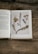 An open book on herbal medicine surrounded by leaves and flowers, signifying knowledge and nature.