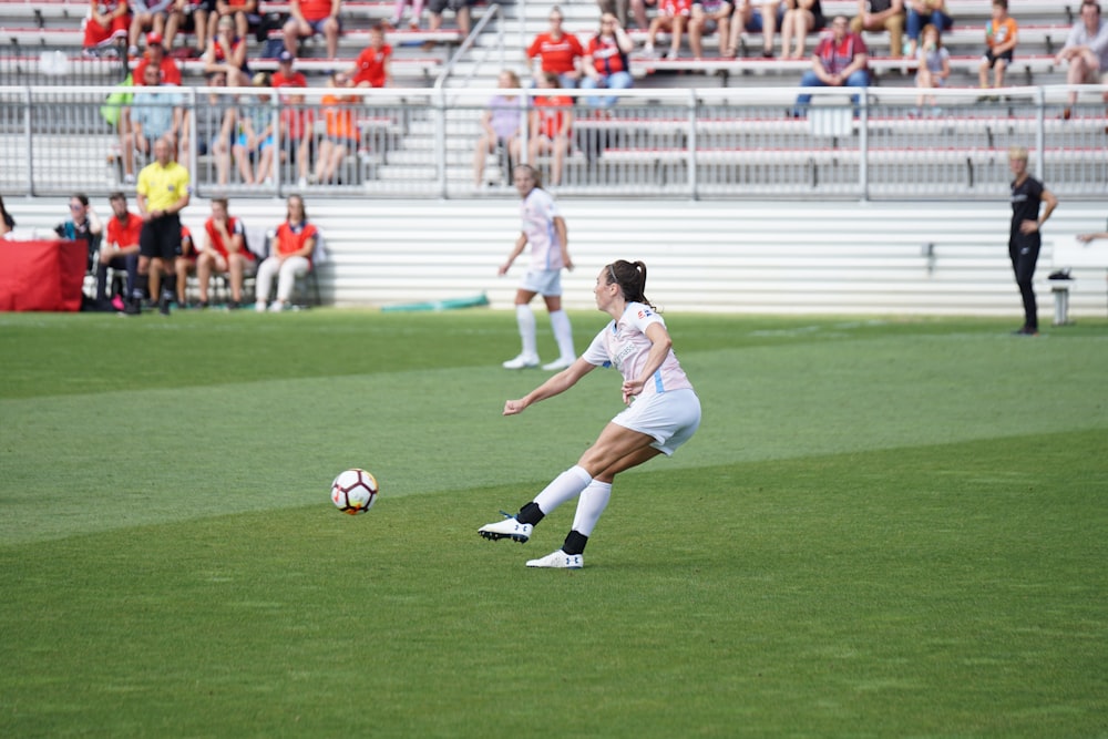 women athletes playing soccer during daytime