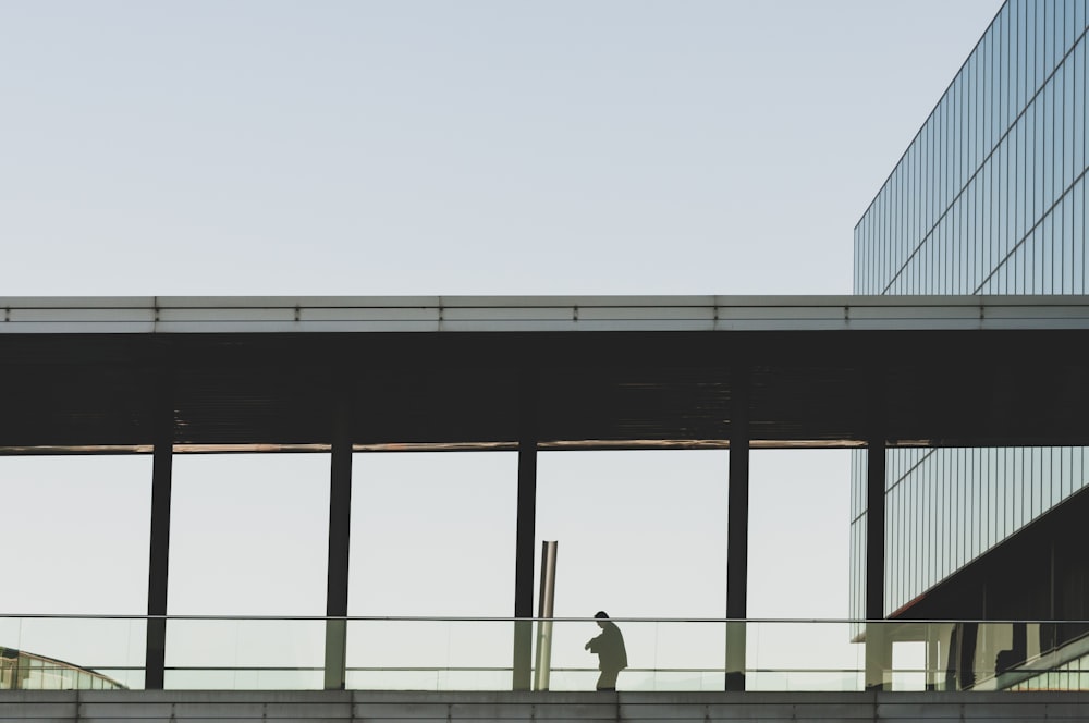 person walking on bridge with roof near building during daytime