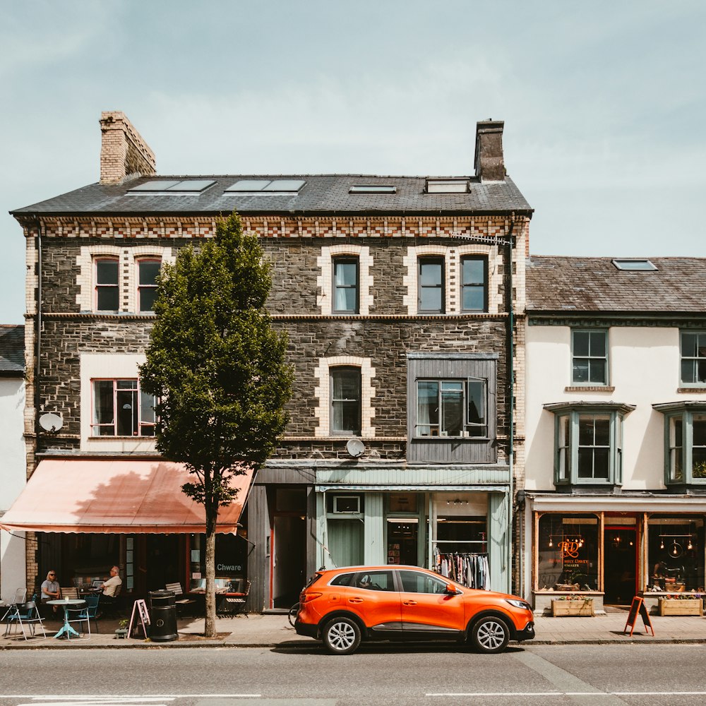 orange SUV beside brown and gray house