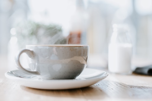 A steaming cup of freshly brewed coffee on a rustic wooden table with soft morning light.