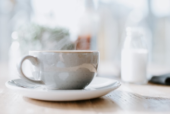 A steaming cup of Solan coffee on a wooden table with mountain scenery in the background.