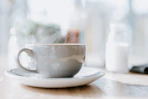 A steaming cup of coffee on a rustic wooden table with mountain scenery in the background.