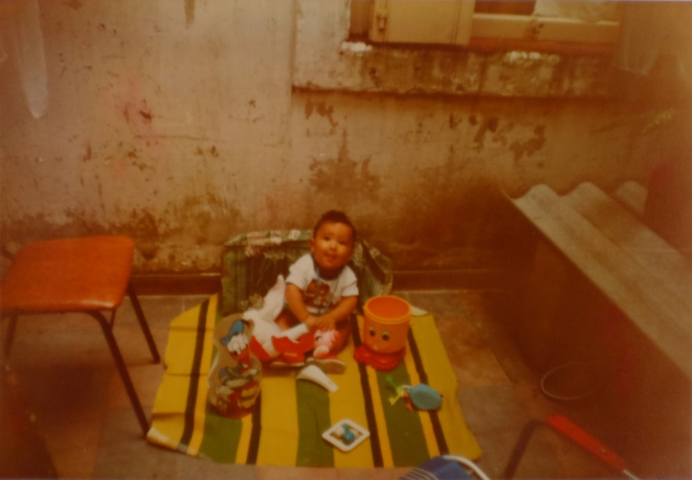 baby sitting on yellow and green textile