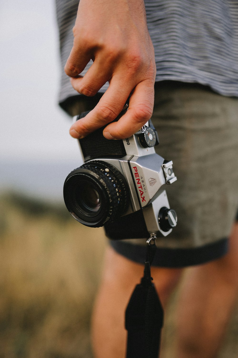 person holding gray and black Pentax camera