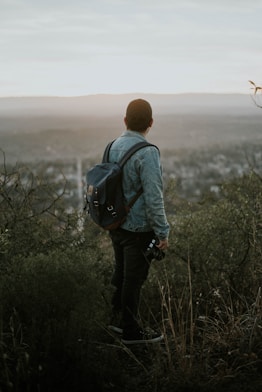 man carrying grey leather backpack