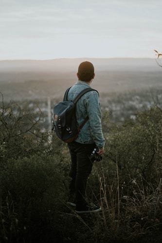 man carrying grey leather backpack