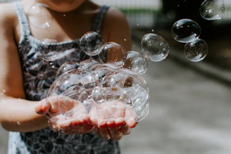 Colorful illustration of a child experimenting with bubbles and light beams.
